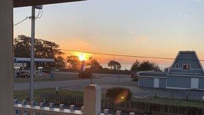 A view from a porch with a white picket fence, overlooking a road with a gas station and a building with a blue roof. - Seabird Lodge (Fort Bragg)