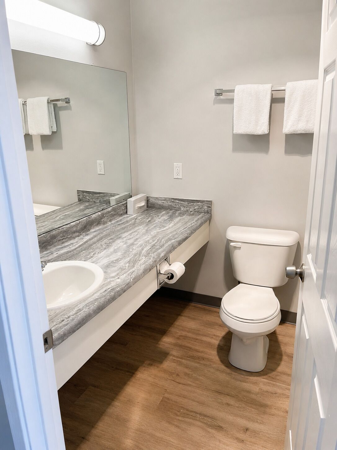 Une salle de bain avec un plan de toilette en marbre, un lavabo blanc, des toilettes et un miroir.