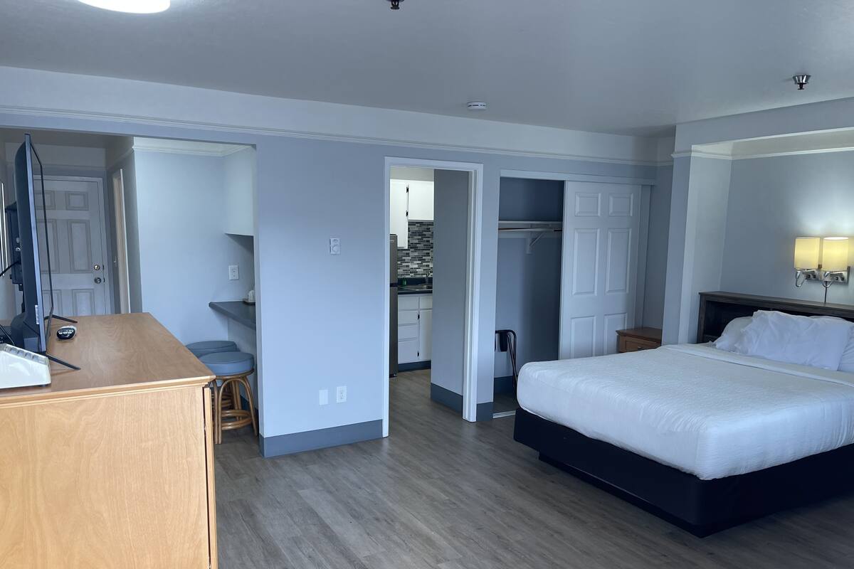 A hotel room with a bed, desk, chair, and a walk-in closet.