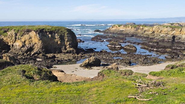 A coastal landscape with rocky cliffs, a sandy beach, and the ocean. - Seabird Lodge (Fort Bragg)
