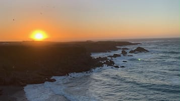 Um pôr do sol costeiro com ondas quebrando nas rochas.