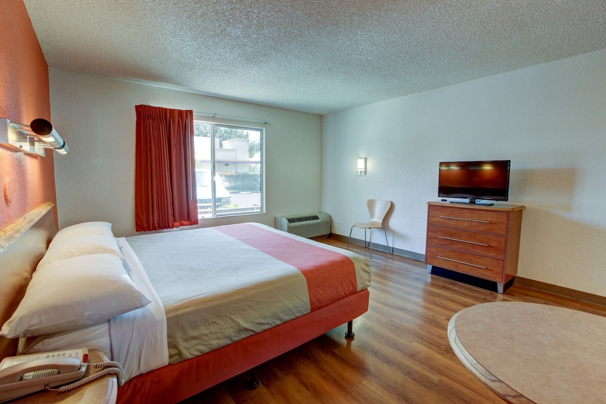 A hotel room with a bed, a TV, a dresser, and a chair.