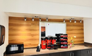 A kitchenette with a microwave, hot water bottles, and a coffee machine.