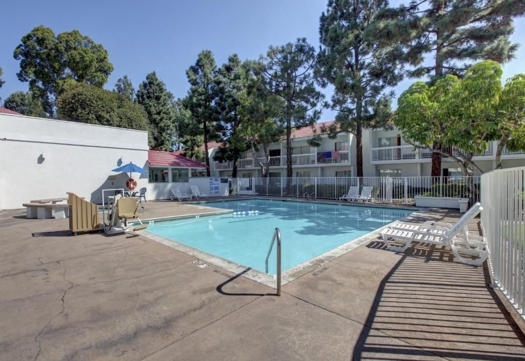 A swimming pool with a metal ladder, lounge chairs, and a covered seating area.