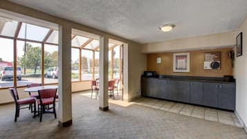 A hotel lobby with a reception desk, seating area, and large windows.