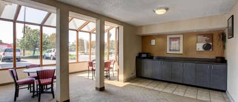 A hotel lobby with a reception desk, seating area, and large windows.