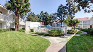 A well-maintained courtyard with a central pathway, surrounded by neatly trimmed hedges and trees. - Motel 6 Irvine - Orange County Airport (Santa Ana)