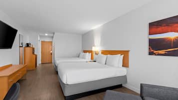 Habitación de hotel con dos camas, televisión, escritorio y un cuadro de un atardecer.