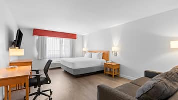 Ein Hotelzimmer mit einem Bett, einem Schreibtisch, einem Stuhl, einer Couch und einem Fernseher.