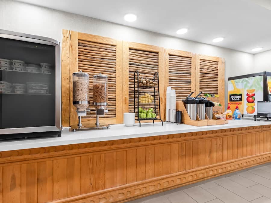 Un área de bebidas autoservicio con un refrigerador, una máquina de café y diversos alimentos.