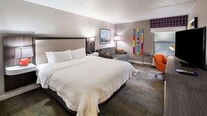 A hotel room with a large bed, a desk with a TV, a chair, and a window with a view. - Hampton Inn Gainesville (Gainesville)