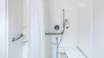 A modern shower area with a glass door, a showerhead, a handheld shower, a handheld showerhead, a shower control panel, and a white shower bench.