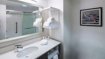 Une salle de bain moderne avec un grand miroir, un lavabo blanc et un porte-serviettes.