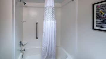 A bathroom with a white bathtub, a shower curtain, and a framed picture on the wall.