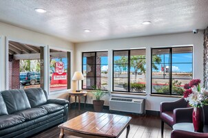 Un hall de hotel con un sofá de cuero, una mesa de centro de madera y un jarrón rojo con flores.