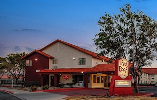 Un edificio de dos pisos con techo rojo y un letrero que indica Red Roof Inn.