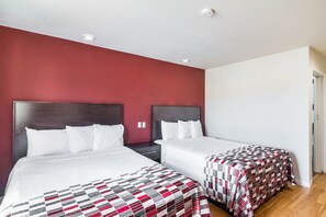 A hotel room with two beds, a red accent wall, and a white ceiling. - Red Roof Inn Palmdale - Lancaster (Palmdale)