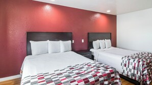 A hotel room with two beds, a red accent wall, and a white ceiling. - Red Roof Inn Palmdale - Lancaster (Palmdale)