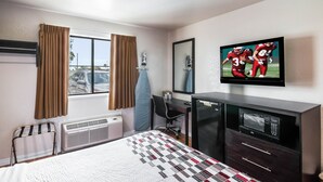 Une chambre d’hôtel équipée d’un lit, d’un bureau, d’une chaise, d’une télévision et d’un four à micro-ondes.