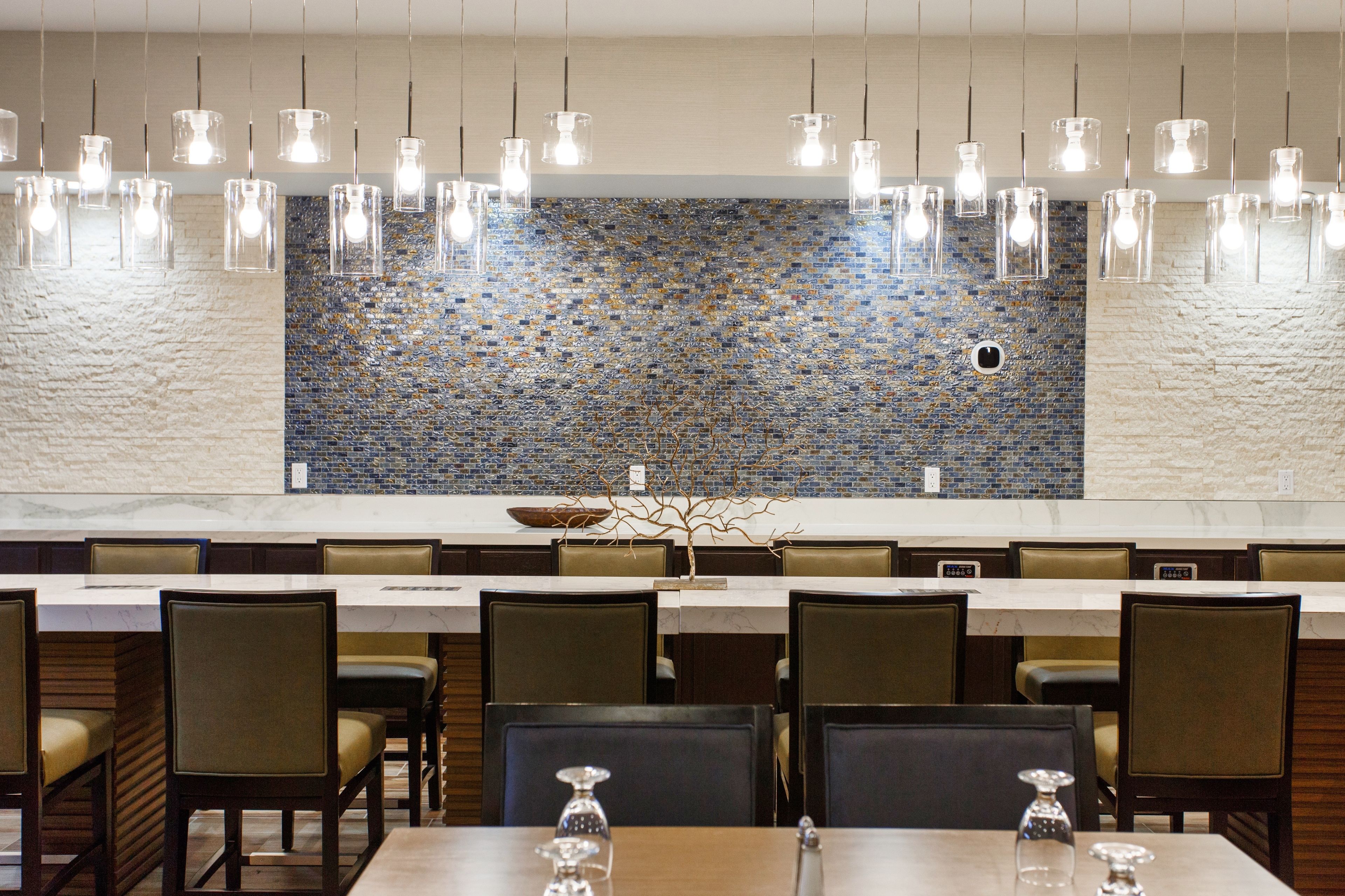 A restaurant with a long counter, multiple tables, and chairs.