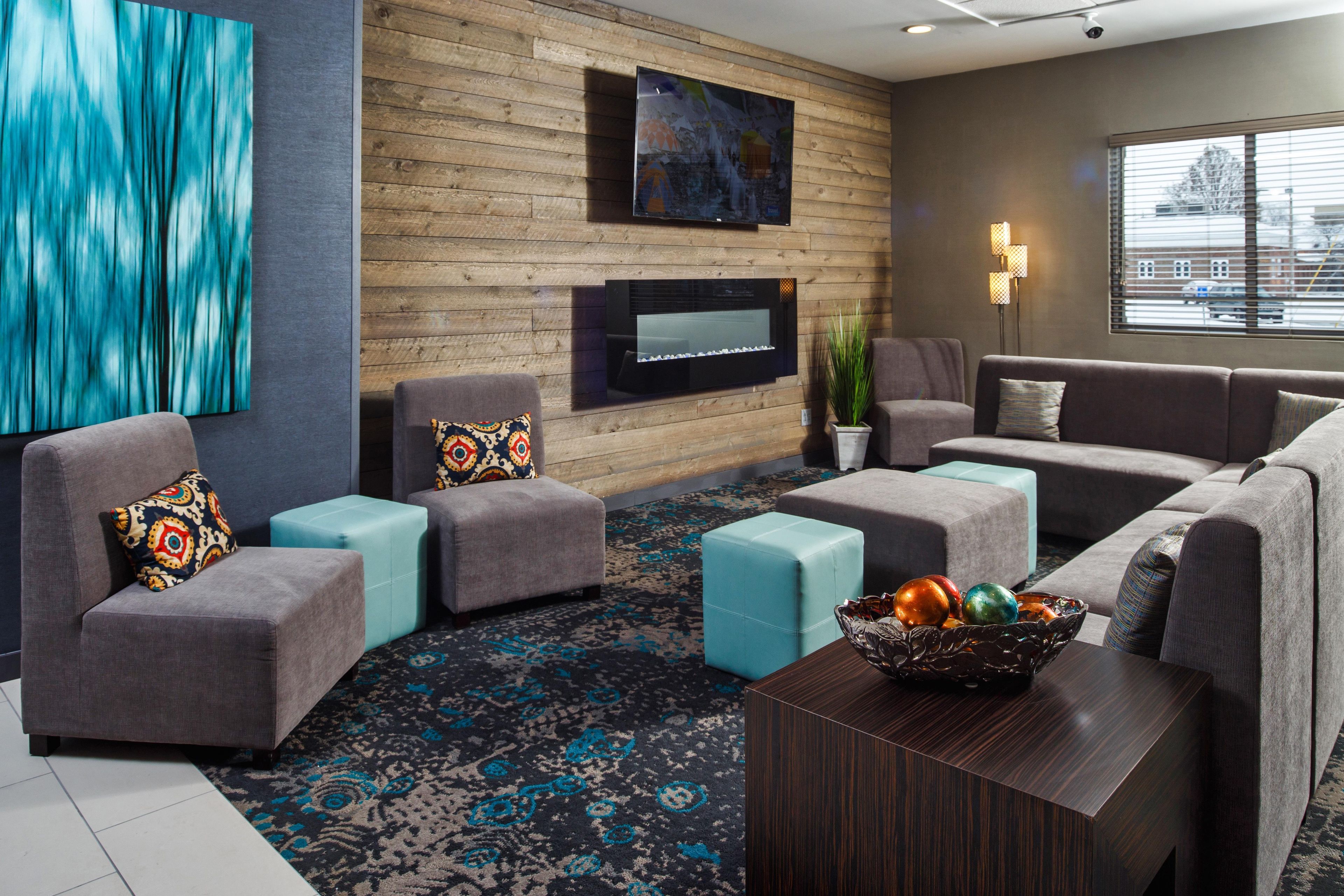 A modern living room with a fireplace, comfortable seating, and a large window.