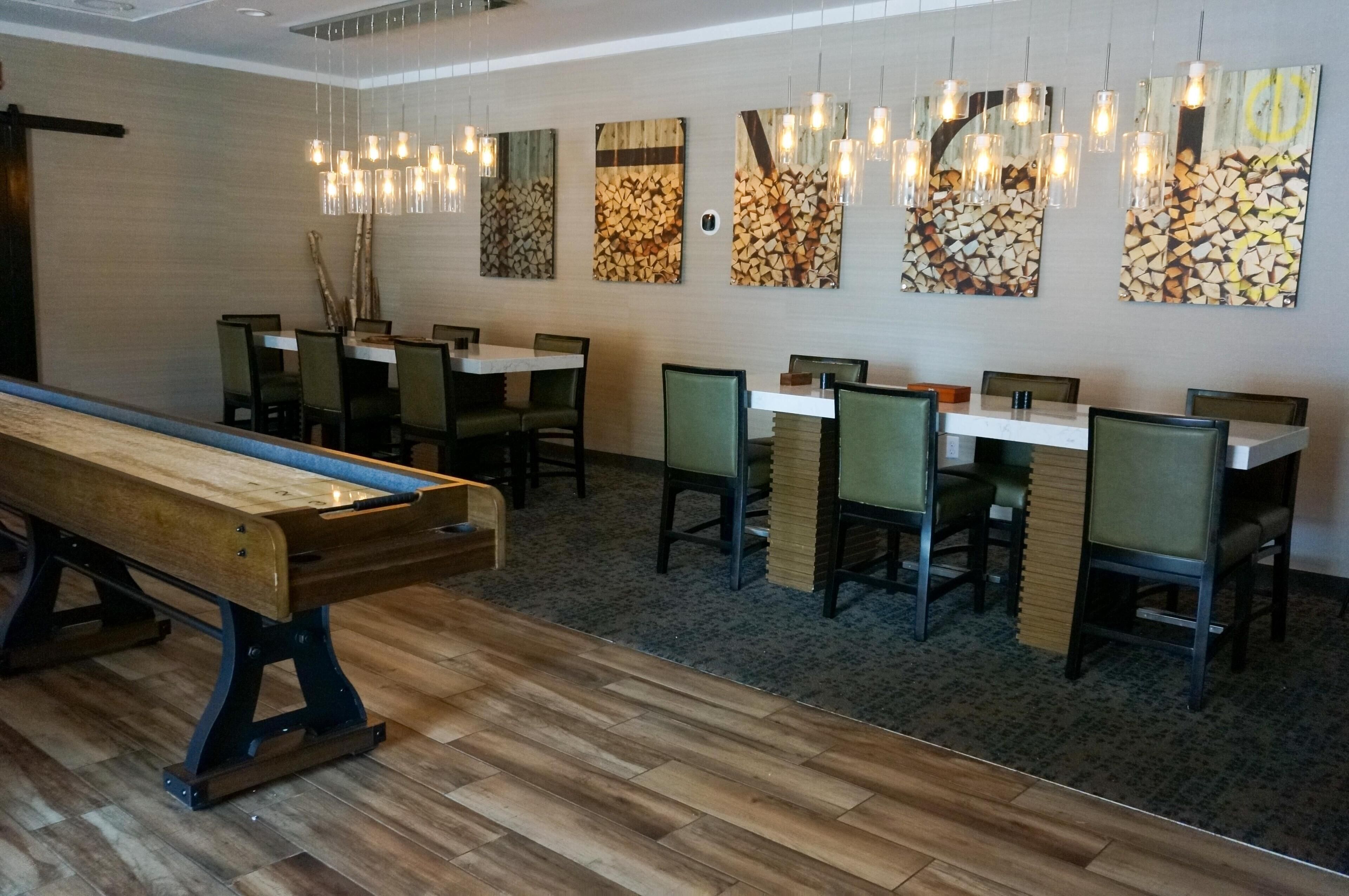 A dining area with wooden tables and chairs, a long bench, and hanging pendant lights.