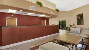A reception area with a wooden reception desk, a sofa, and a coffee table. - Days Inn by Wyndham Globe (Globe)