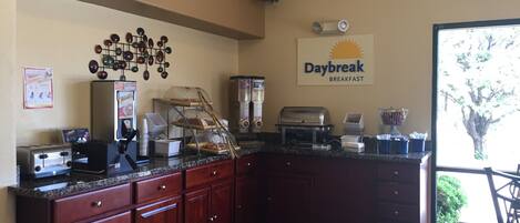 A breakfast area with a Daybreak sign, a coffee machine, a toaster, and a salad bar.