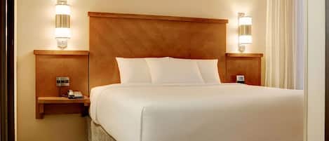 Una habitación de hotel con una cama grande, dos mesitas de noche con lámparas y un cabecero de madera.