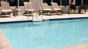 A swimming pool with lounge chairs and a small table. - Sonesta Select Atlanta Duluth  (Duluth)