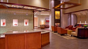 A modern lobby with a reception desk, seating area, and a decorative wall with abstract art. - Sonesta Select Atlanta Duluth  (Duluth)