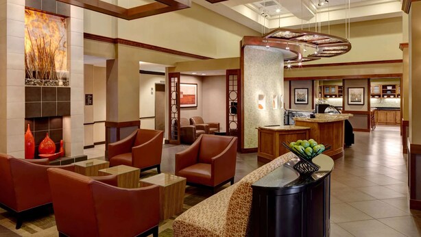 A spacious lobby with leather seating, a fireplace, and a kitchen area. - Sonesta Select Atlanta Duluth  (Duluth)