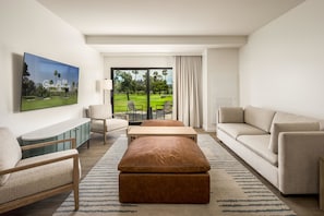 A modern hotel room with a large window, a sofa, a coffee table, a TV, and a cabinet. - Guesthouse Hotel at La Valle (Rancho Santa Fe)