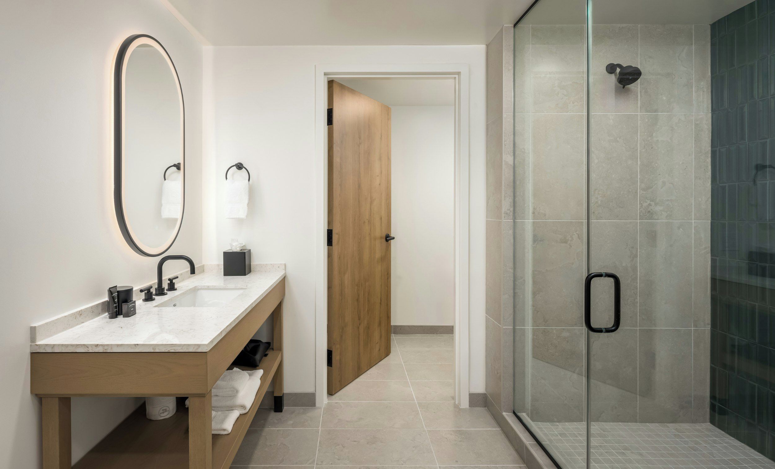 Un baño moderno con tocador de madera, un espejo grande y cabina de ducha con paredes de vidrio.