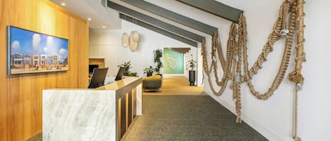 Un espace d’accueil doté d’un comptoir en marbre, de lambris en bois, d’un tableau et d’une installation artistique originale réalisée avec des cordes.