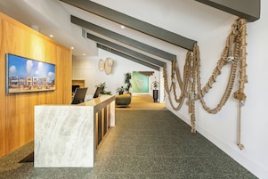 Een receptie met een marmeren balie, houten lambrisering, een schilderij en een bijzondere installatie van touwkunst.