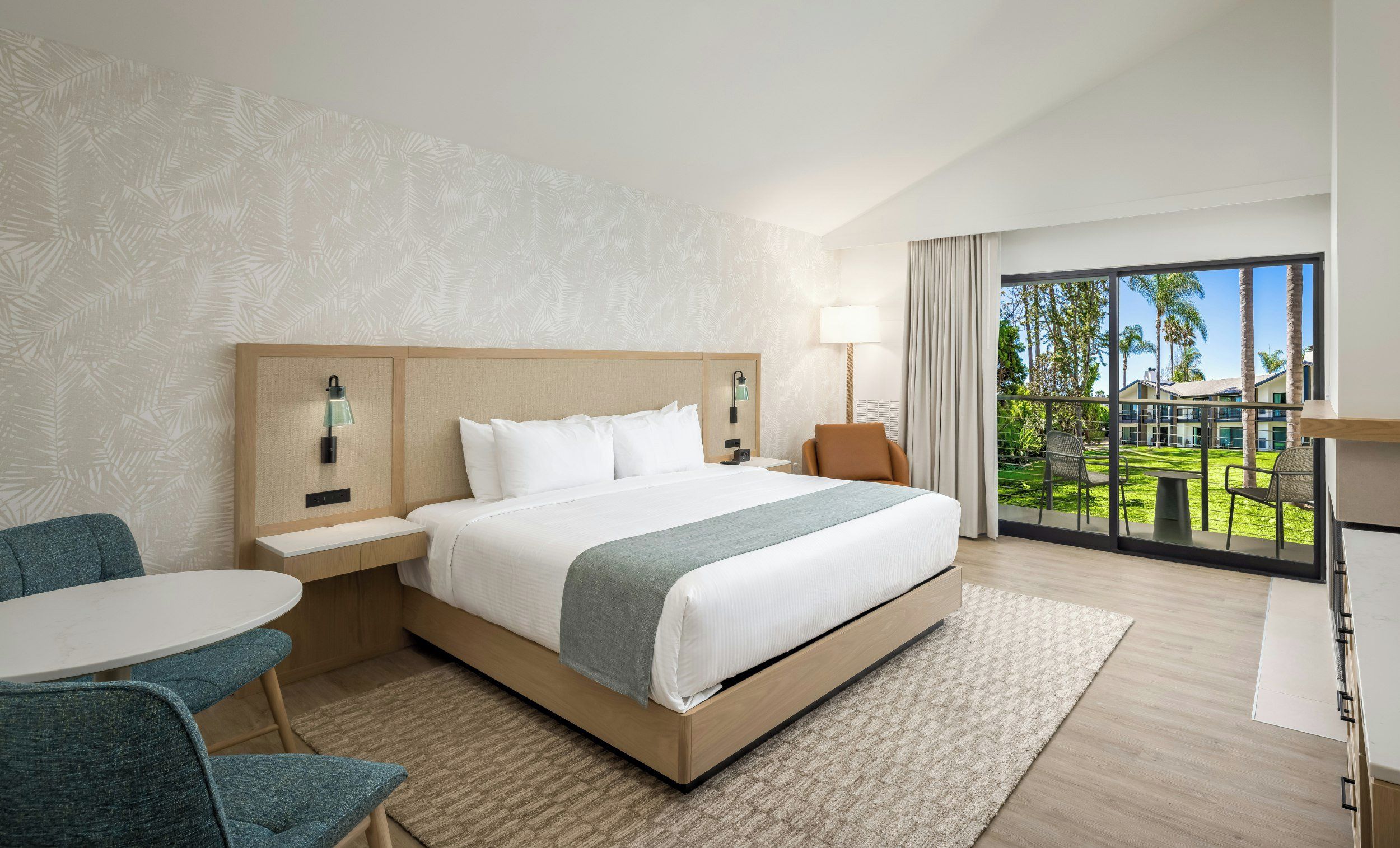 Una habitación de hotel con una cama grande, un escritorio, una silla y vistas al exterior.