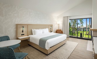 Una habitación de hotel con una cama grande, un escritorio, una silla y vistas al exterior.