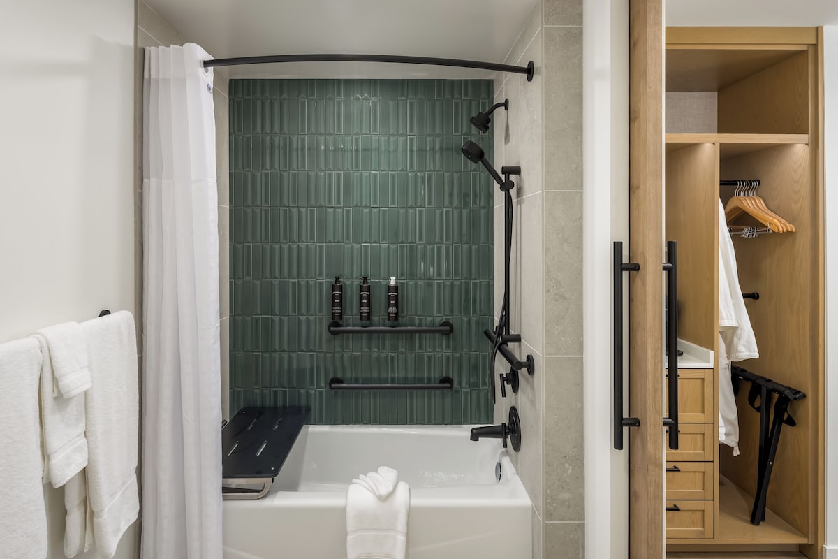 A modern bathroom with a freestanding bathtub, a showerhead, and a towel rack.