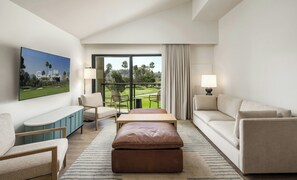 A hotel room with a large window, a flat-screen TV, a sofa, a loveseat, a coffee table, and a side table with a lamp. - Guesthouse Hotel at La Valle (Rancho Santa Fe)