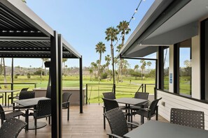 A covered outdoor seating area with tables and chairs, overlooking a golf course. - Guesthouse Hotel at La Valle (Rancho Santa Fe)