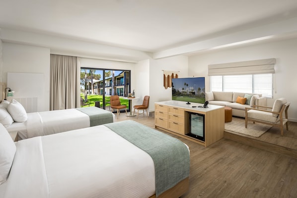 A hotel room with two beds, a desk, a television, and a view of the outdoors. - Guesthouse Hotel at La Valle (Rancho Santa Fe)