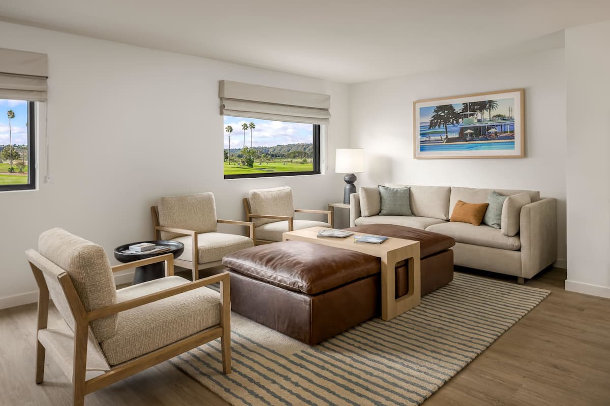 A modern living room with a sofa, chairs, a coffee table, and a painting on the wall.