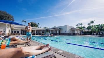Una piscina al aire libre, sombrillas, sillones reclinables de piscina