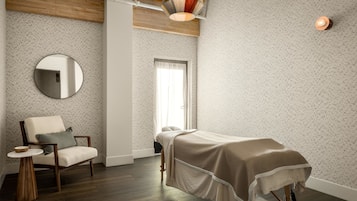 A room with a bed, a chair, a round mirror, and a small table.