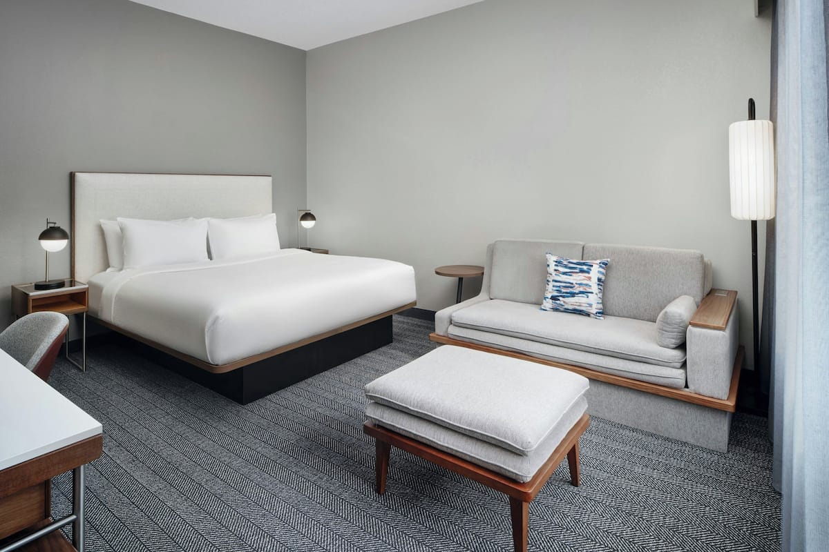 A hotel room with a bed, a sofa, a small table, and a desk.