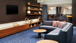Eine moderne Hotelhalle mit einem Ecksofa, einem langen Holztisch und einem flachbildfernseher an der Wand.