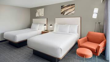Een hotelkamer met twee bedden, een stoel en een lamp.