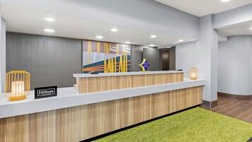A hotel reception desk with a modern design, a nameplate, and a decorative wall piece.