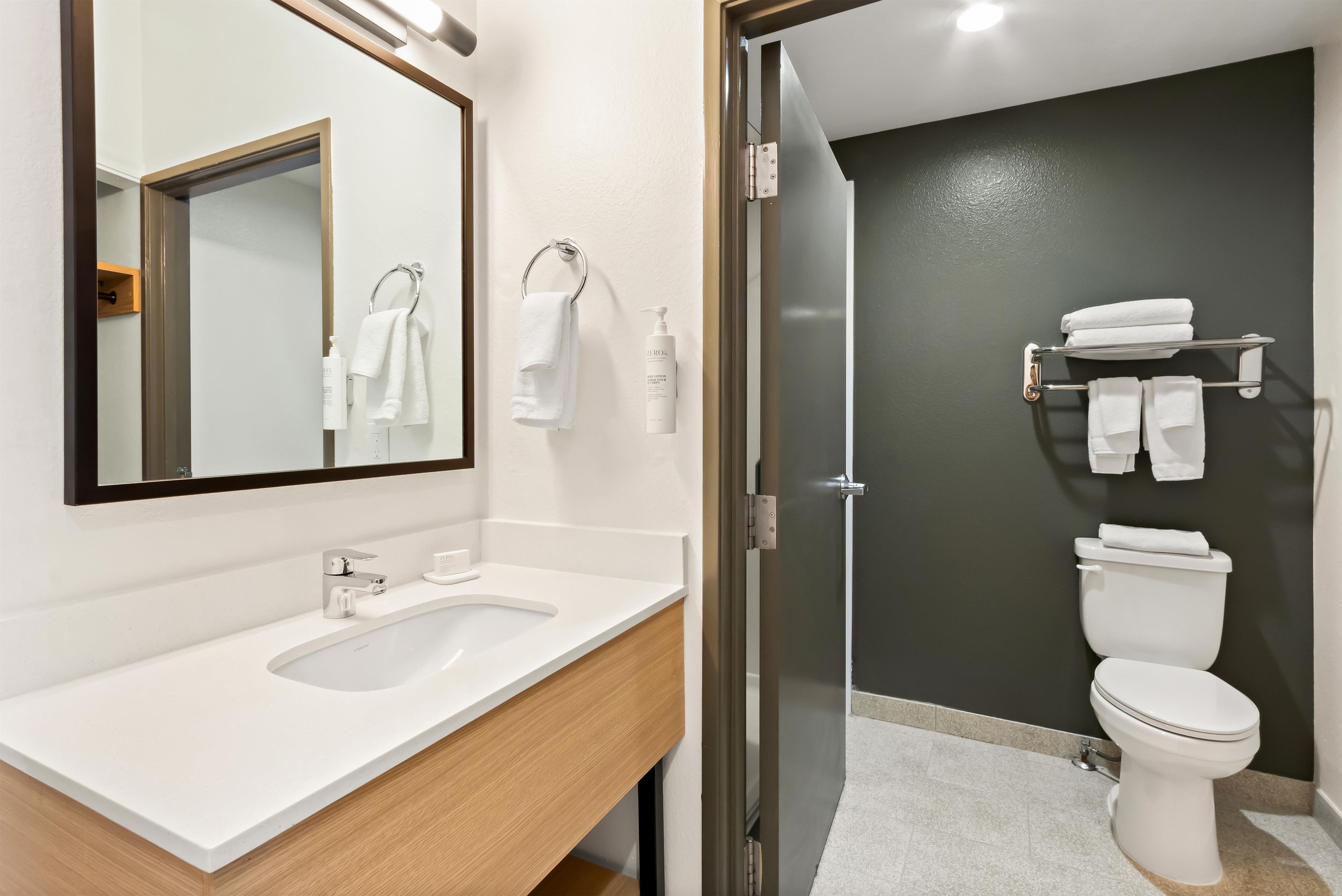 A modern bathroom with a white sink, a mirror, a toilet, and a glass shower enclosure.